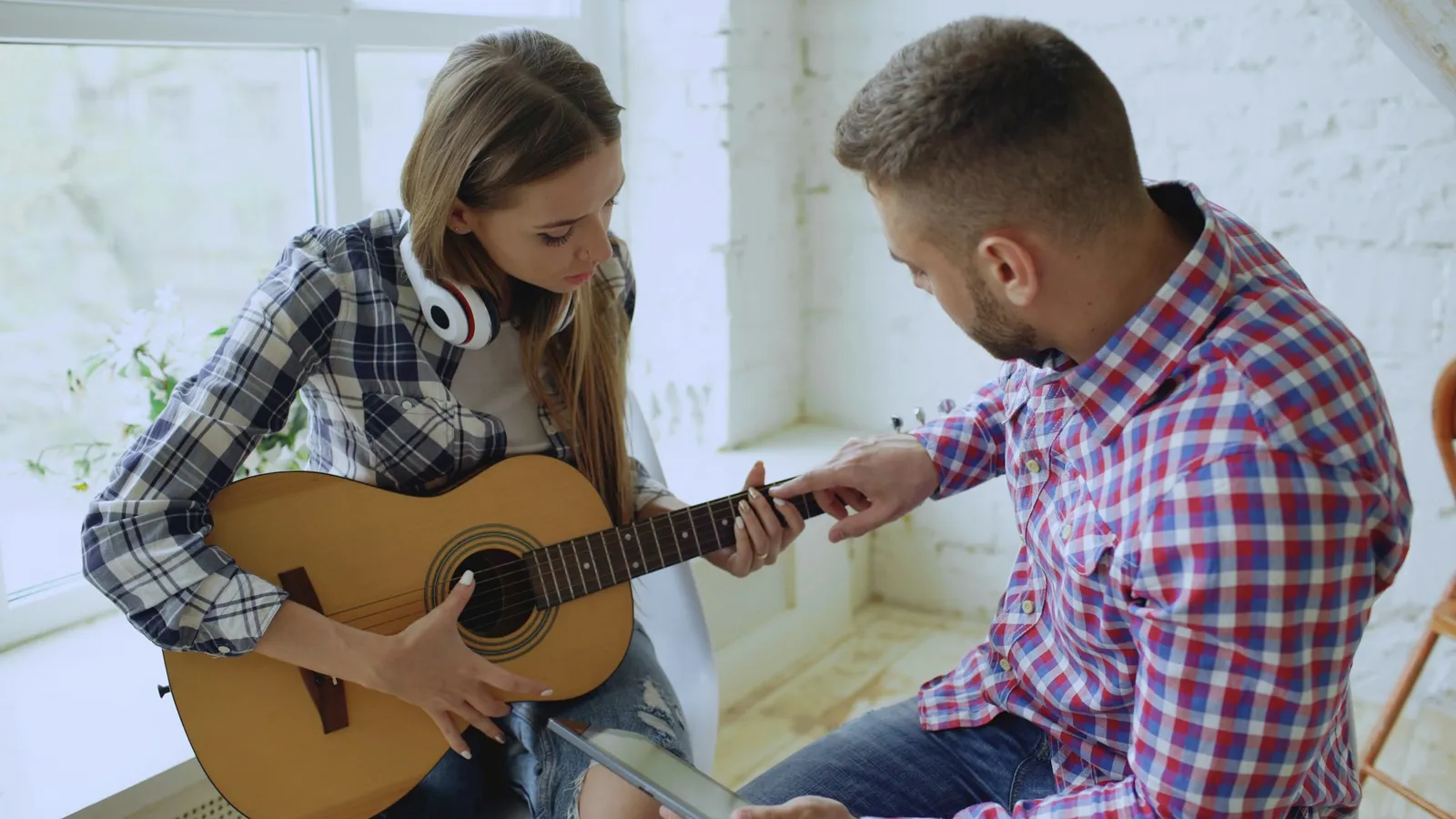 Profesor de guitarra enseñando a una alumna en una clase de música
