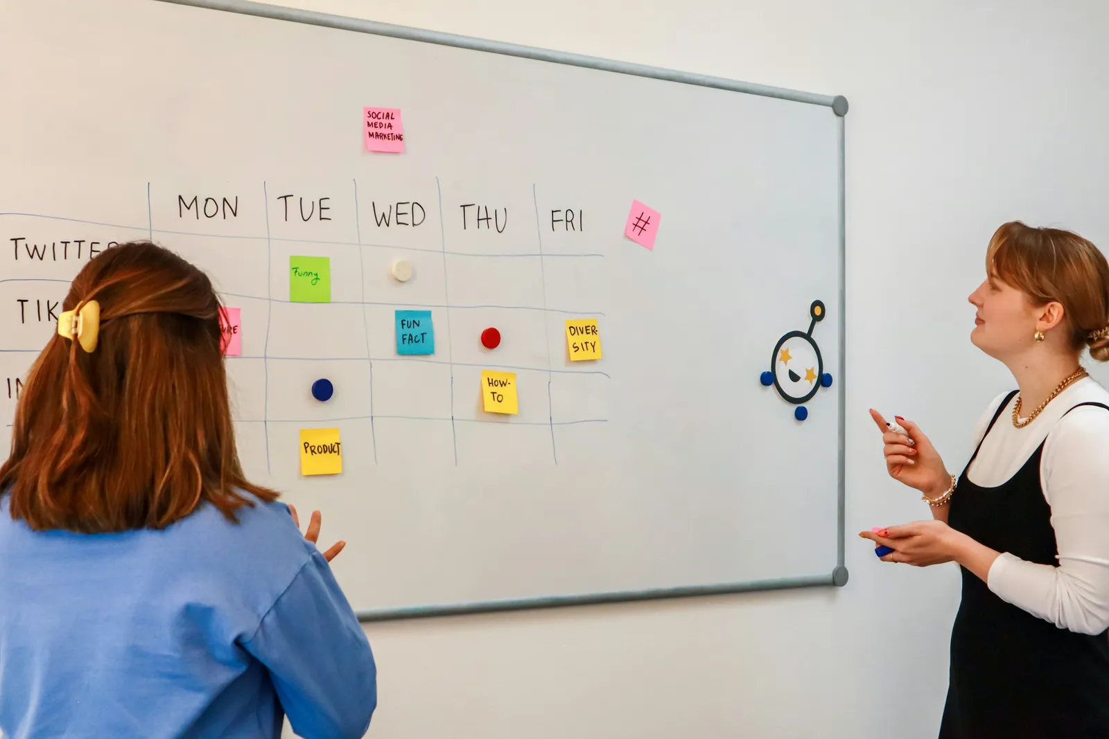 Dos personas organizando la planificación de cursos y grupos en una pizarra