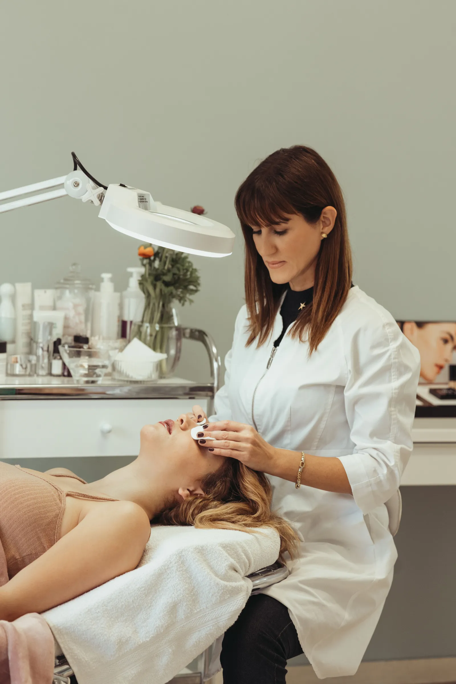 Profesional aplicando un tratamiento facial en una sala de estética luminosa y cuidada
