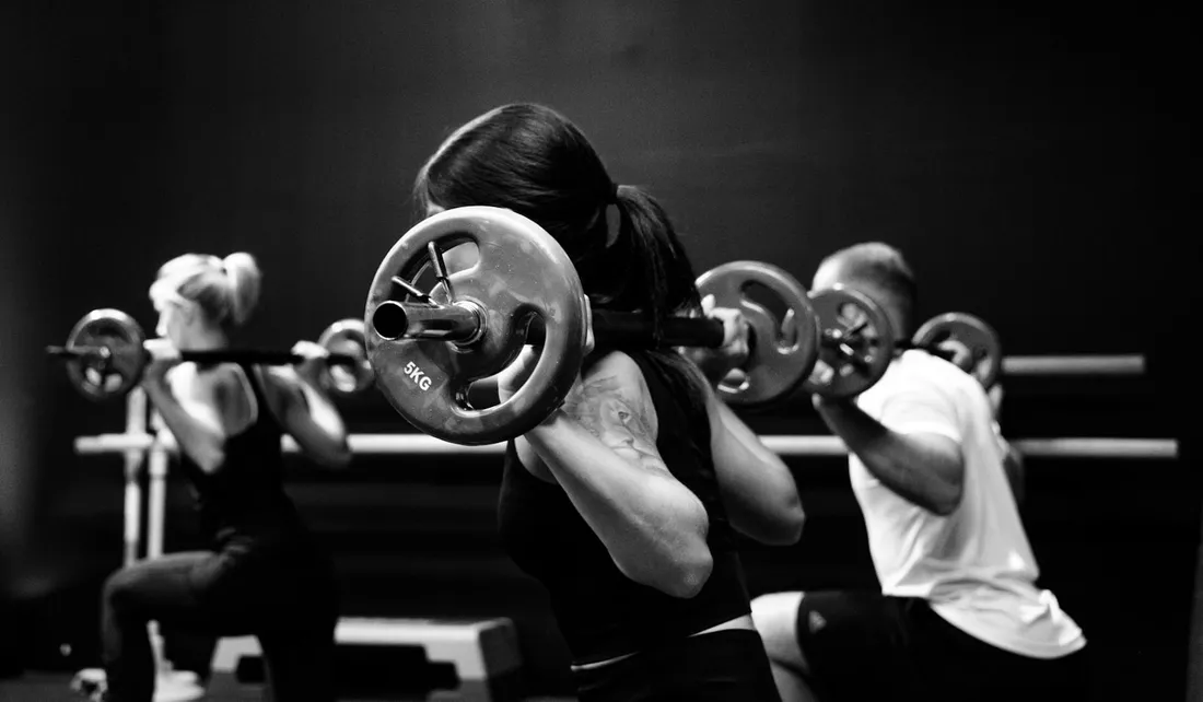 Grupo de socios entrenando fuerza juntos en el gimnasio