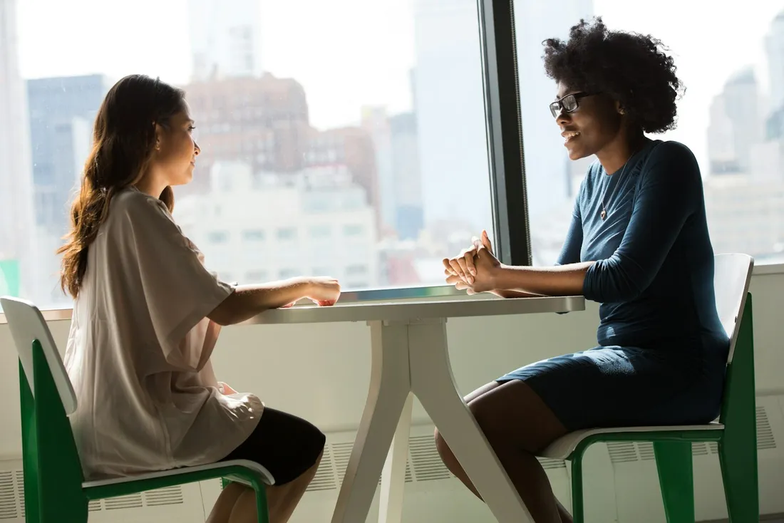 Dos mujeres conversando junto a una mesa durante una consulta