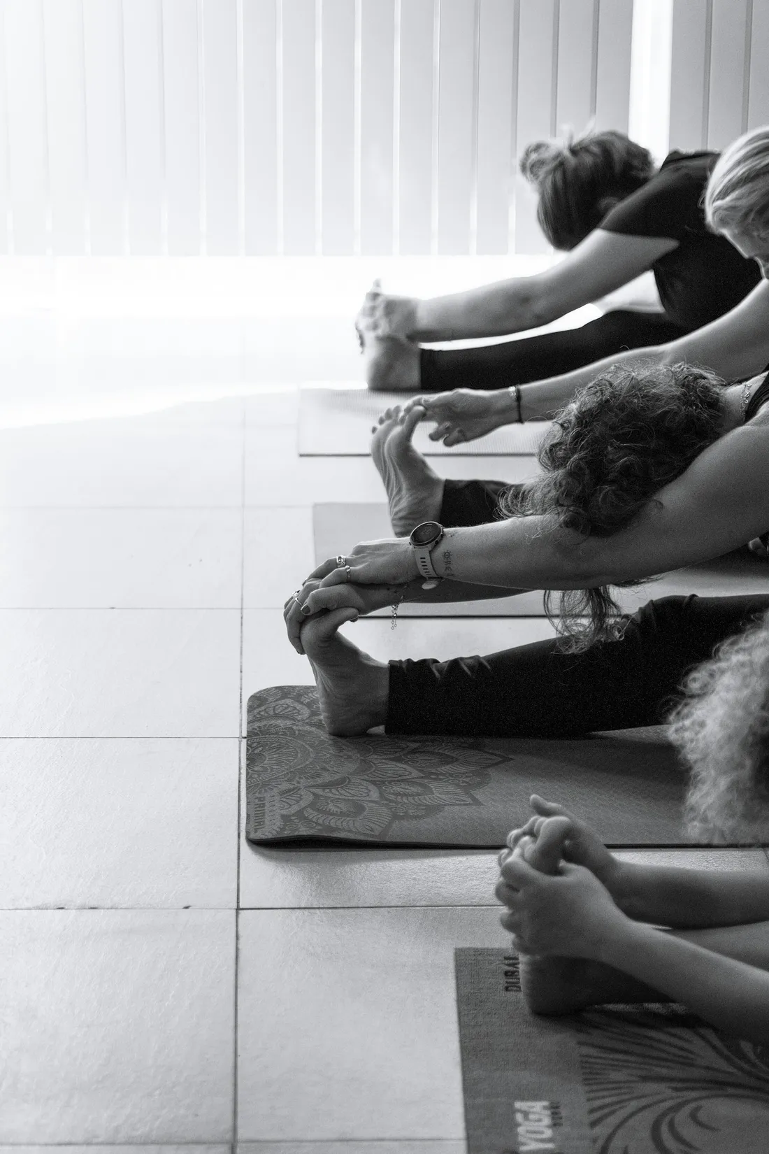 Instructora guiando una postura de yoga a una alumna en un estudio luminoso